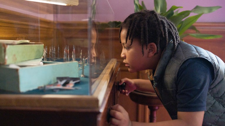 A boy looking into a display case containing toys at Lanhydrock